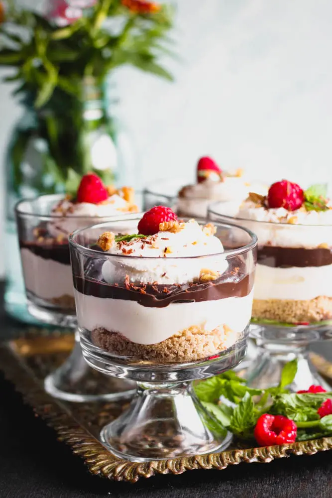 closeup shot of Chocolate Cheesecake Trifles layered in individual trifle dishes served with fresh raspberry and mint as garnish