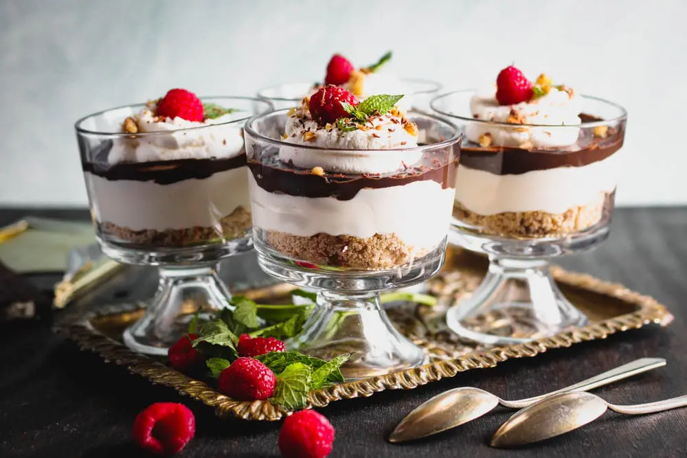 Chocolate Cheesecake Trifles layered in individual trifle dishes served with fresh raspberry and mint as garnish