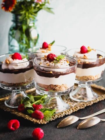 Chocolate Cheesecake Trifles layered in individual trifle dishes served with fresh raspberry and mint as garnish