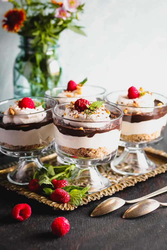 Chocolate Cheesecake Trifles layered in individual trifle dishes served with fresh raspberry and mint as garnish