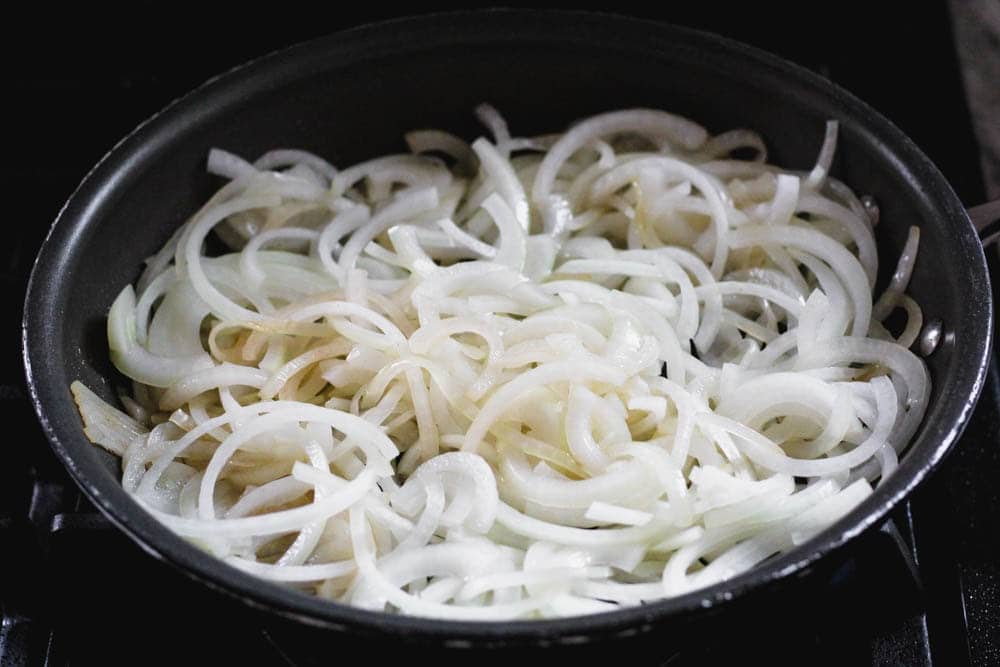 raw onions just added to a saute pan to begin caramelizing