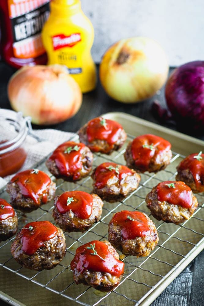 Mini meatloaf dressed in a ketchup based dressing on a sheet pan line with a cooling rack