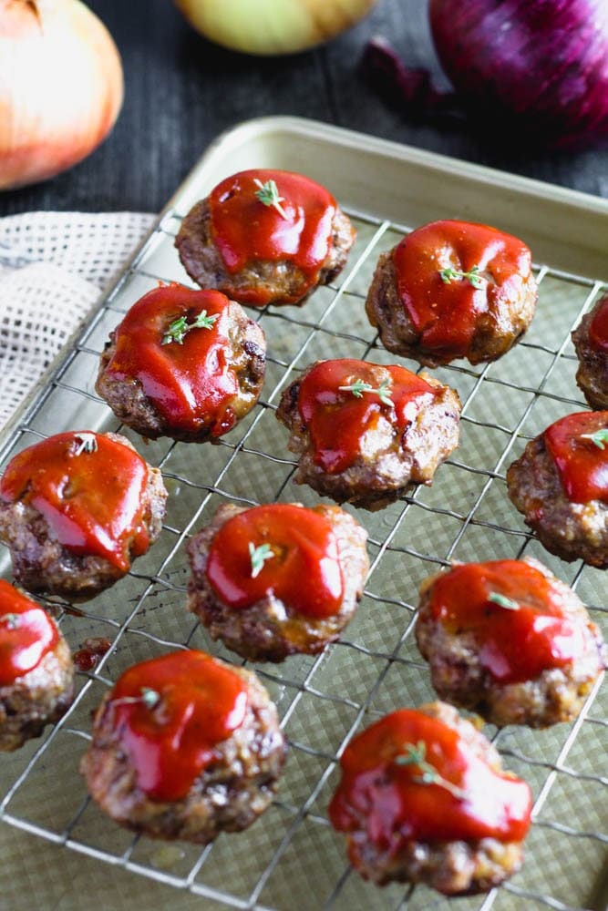 Mini meatloaf dressed in a ketchup based dressing on a sheet pan line with a cooling rack