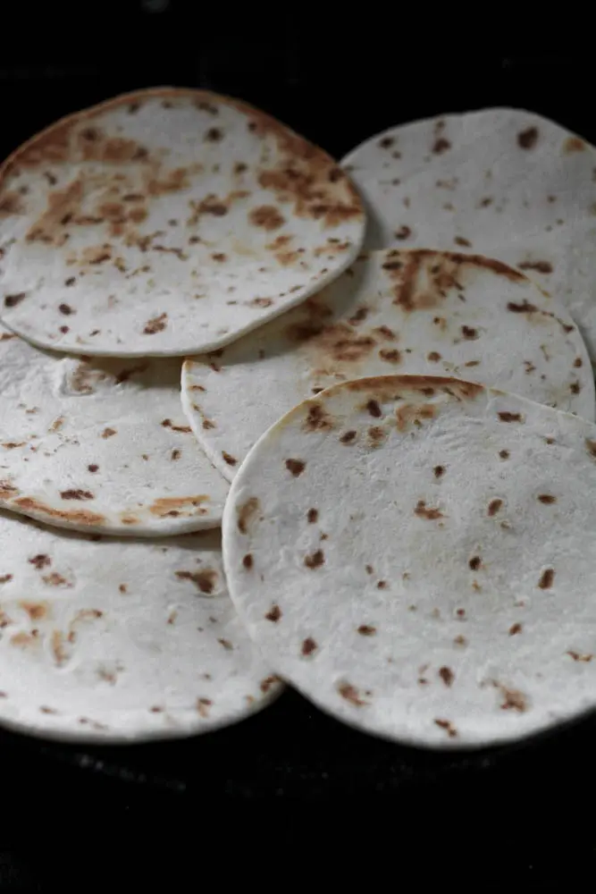 browned flour tortillas overlapping on a black surface