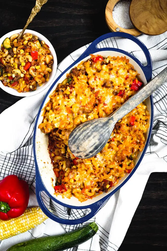 an oval shaped blue casserole dish filled with an orange and red pasta casserole