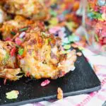 two pieces of colorful cereal crusted shrimp on a black board
