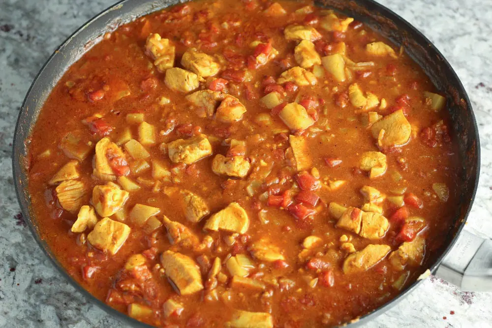 prepared red chicken curry in a large black round skillet