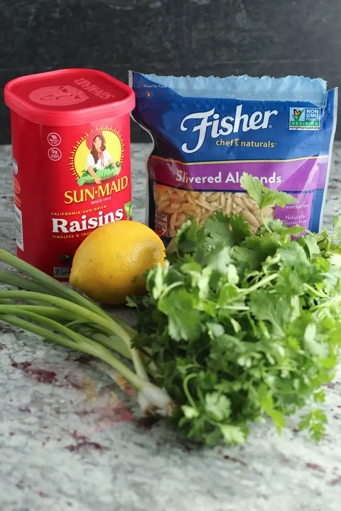 garnishes including raisins, slivered almonds, bunch of cilantro, whole lemon, and green onions