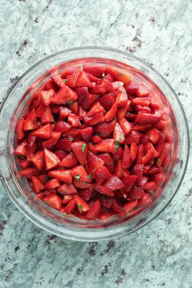 overhead view of red strawberry pieces layered over angel food cake as the second layer in strawberry trifle