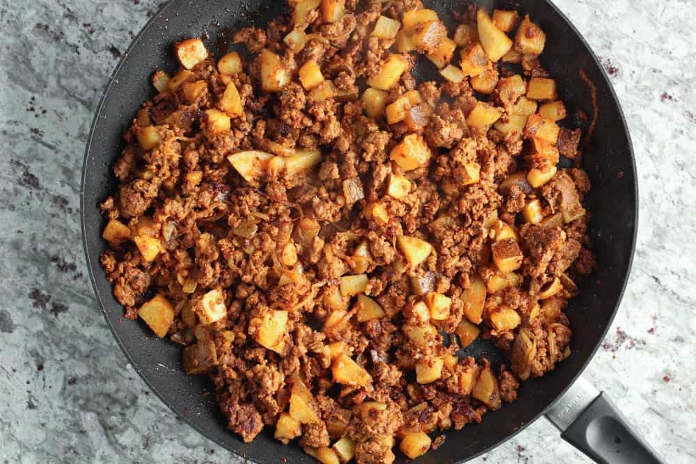 Cooked chorizo, potato and onion in a large black saute pan