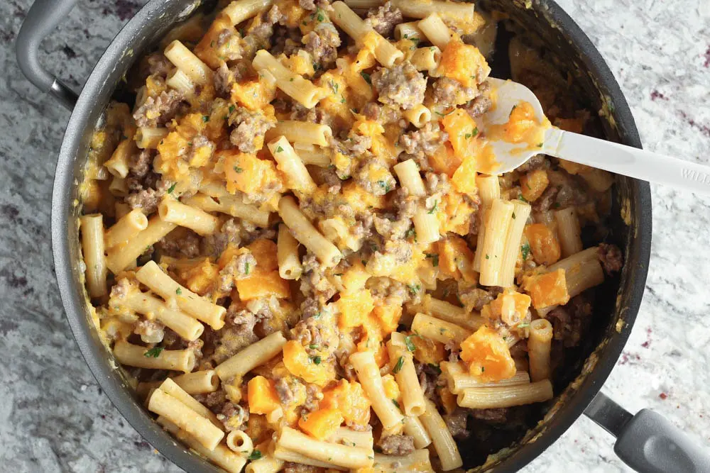 the completed recipe mixed together in a large high rimmed saute pan featuring butternut squash, rigatoni and sausage