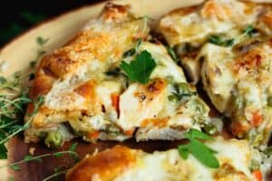 three triangular pieces of chicken potpie crostata with a rich brown crust and creamy white chicken filing with flecks of orange from the carrots and green from the peas served on a wooden platter