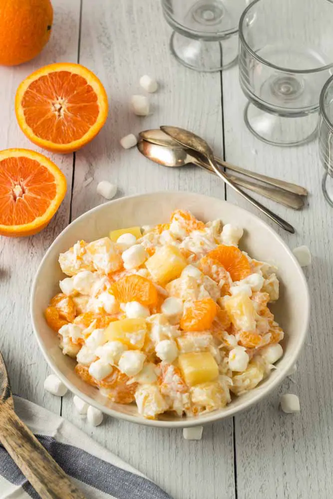 Five Cup Salad mixed and prepared in a large glass mixing bowl with mini marshmallows scattered around