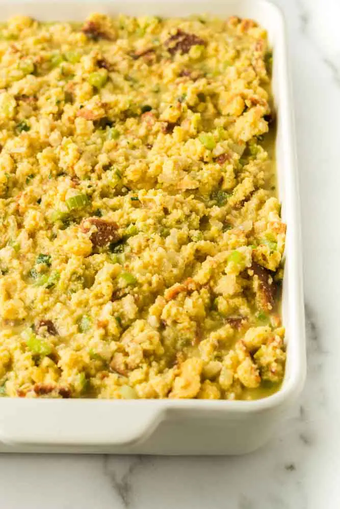 white casserole dish filled with uncooked traditional southern cornbread dressing