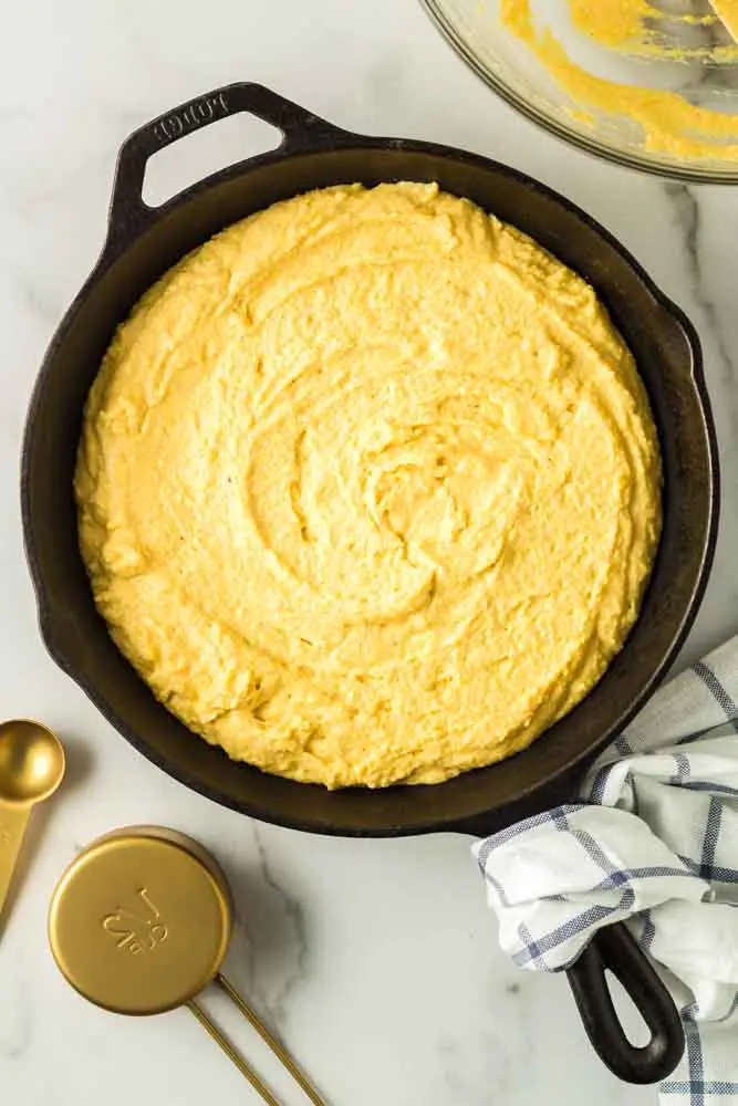 prepared cornbread batter in a black cast iron pan