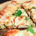 three triangular pieces of chicken potpie crostata with a rich brown crust and creamy white chicken filing with flecks of orange from the carrots and green from the peas served on a wooden platter