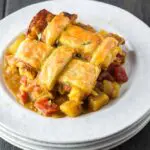 Chicken curry pot pie dished out onto a white plate featuring a golden brown lattice puff pastry topping
