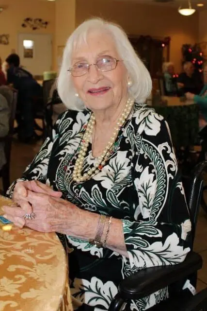 Elderly female smiling with her hands on a table