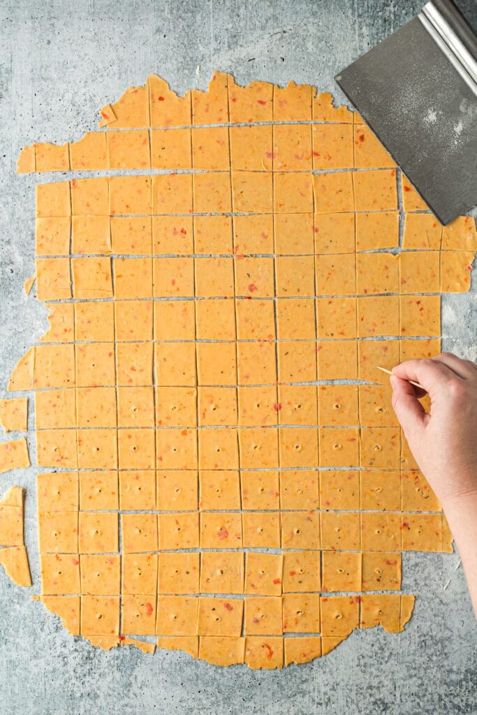 homemade cheez it dough rolled out and cut into perfect squares with a whole being poked in each one