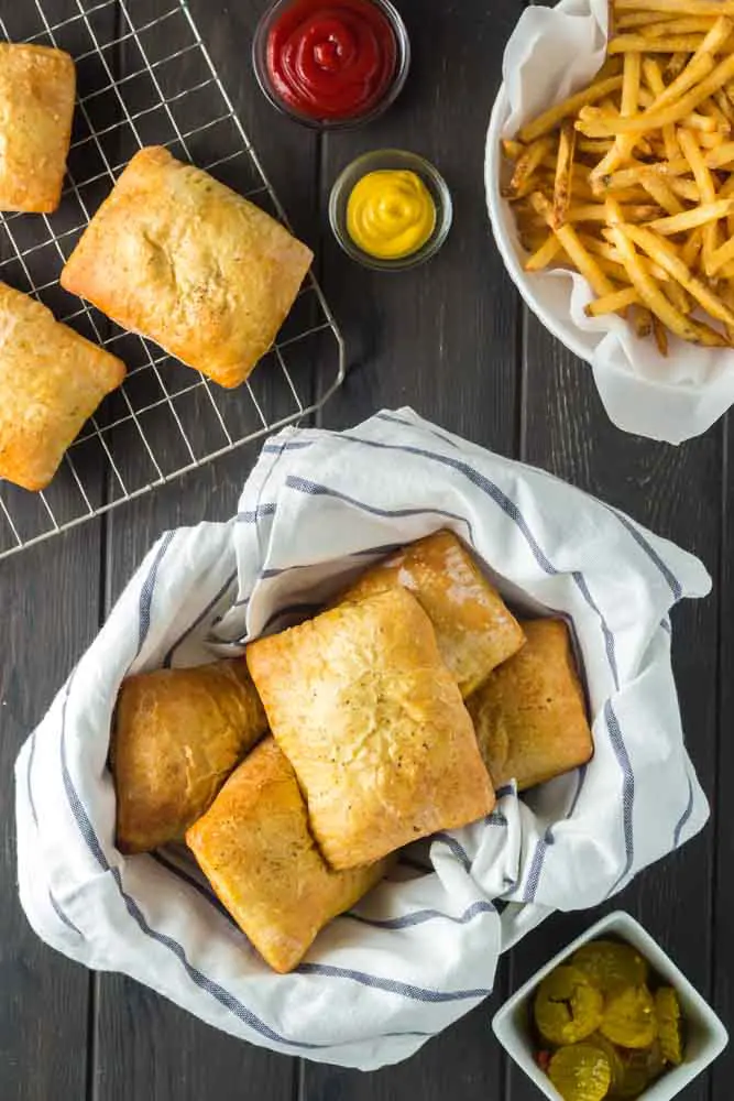 pimento cheeseburger hand pies in a basket lined with a blue and white towel with a side of french fries
