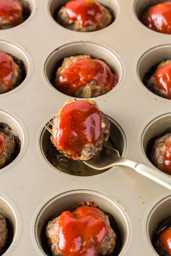 Onion Burger Mini Meatloaf covered in bright red sauce being lifted out with a fork