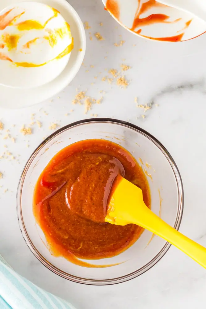 Bright red meatloaf sauce in a small glass mixing bowl