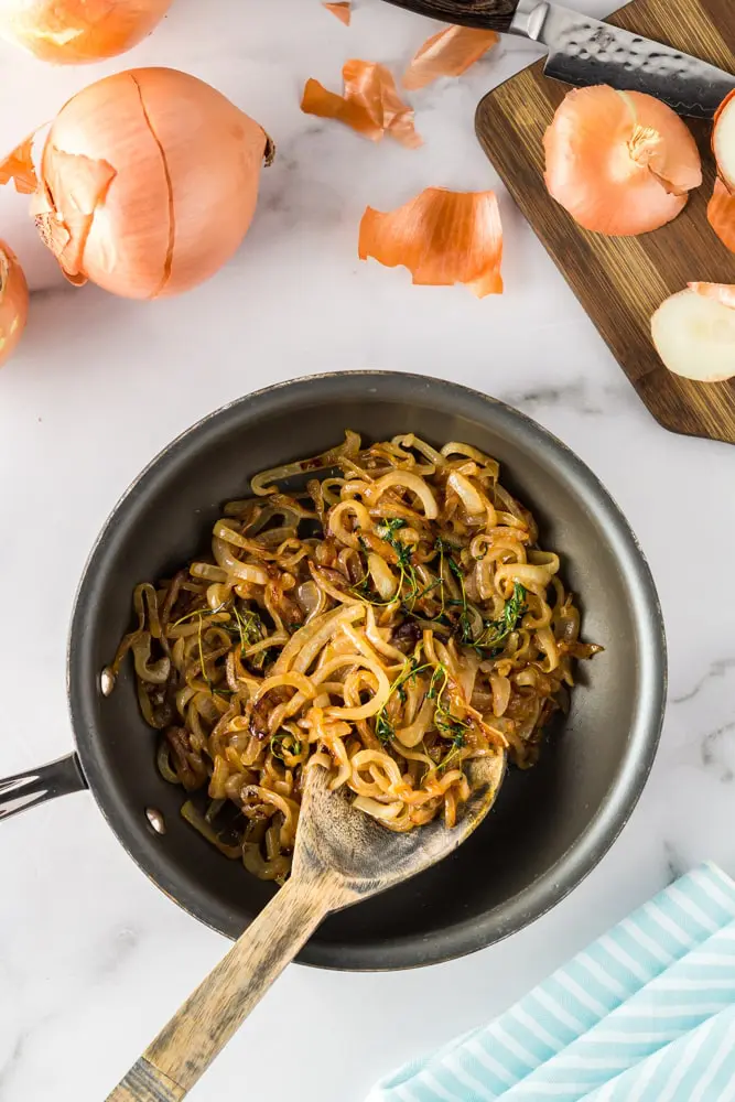 golden caramelized onions in a black saute pan with thyme sprigs