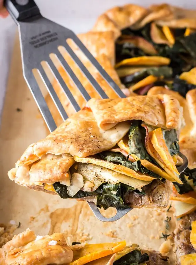 Slice of sweet potato, apple, and kale galette being picked up with a silver spatula