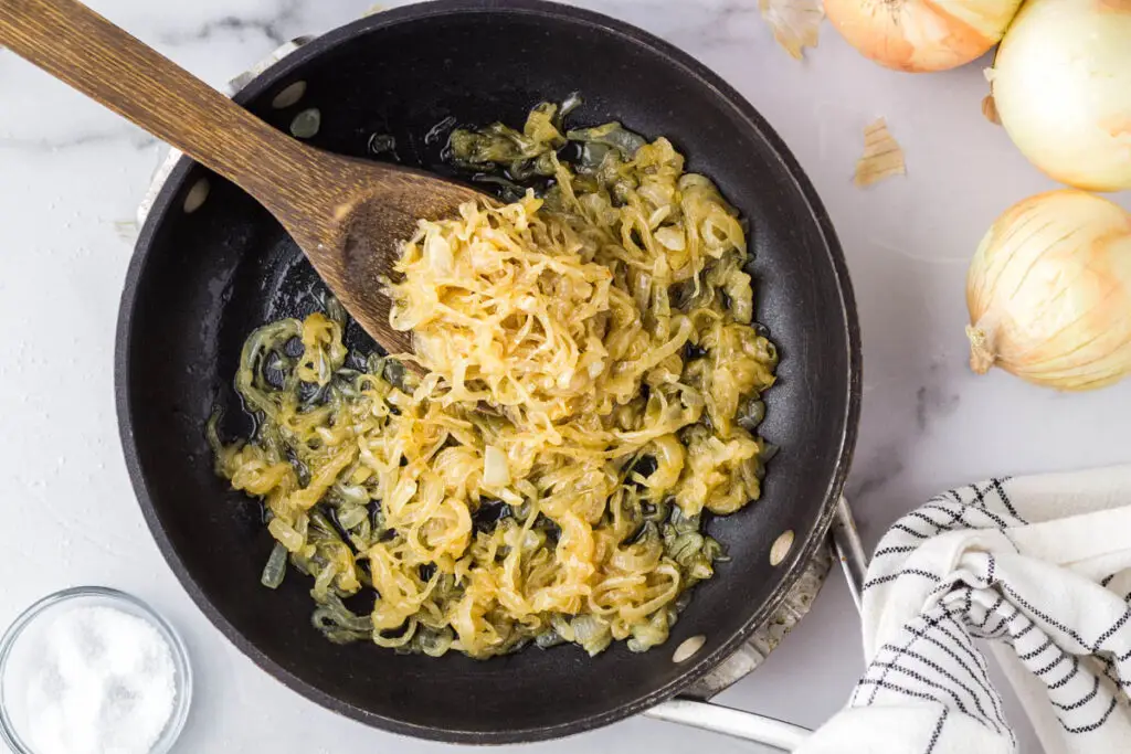 caramelized onions in a saute pan with a wooden spoon