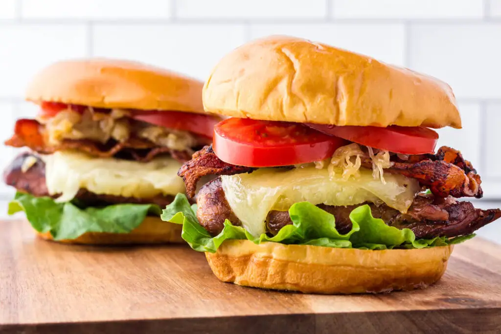 Two hawaiian chicken sandwiches on a wooden cutting board