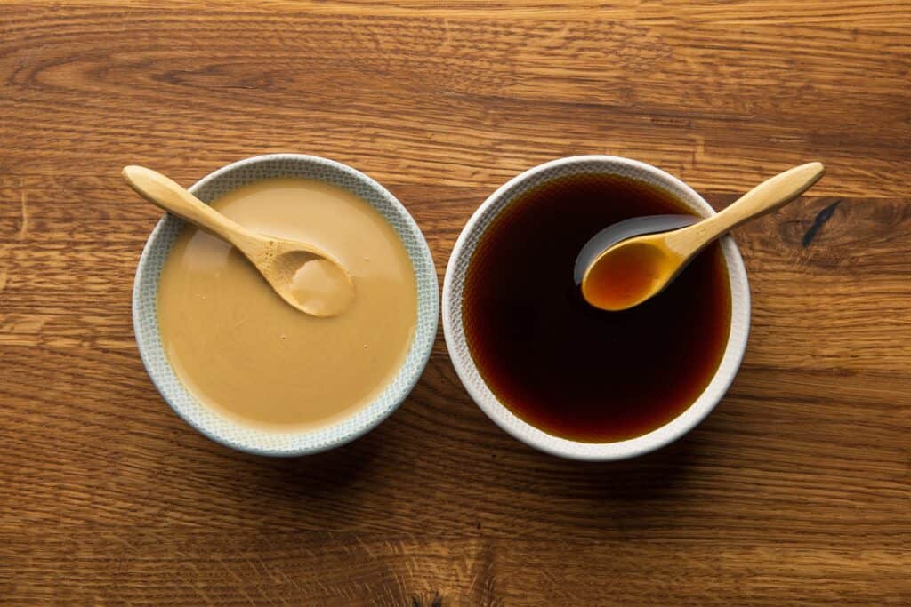 bowl of tahini and bowl of sesame oil sitting side by side.
