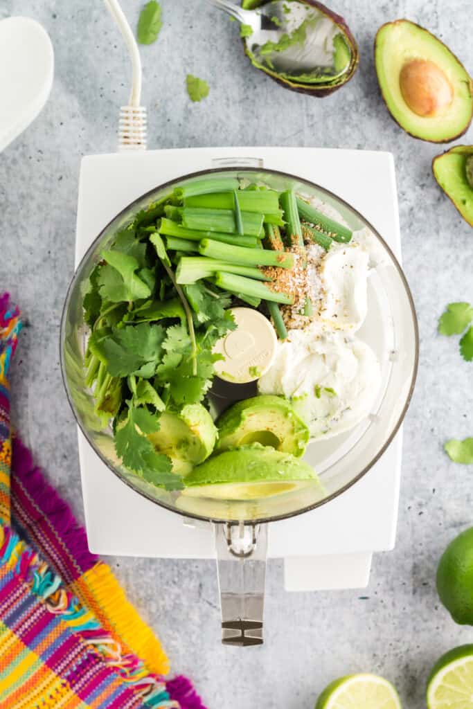 creamy avocado sauce ingredients in a food processor bowl.