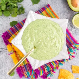 green avocado sauce for tacos in a white star-shaped bowl on a festive napkin.