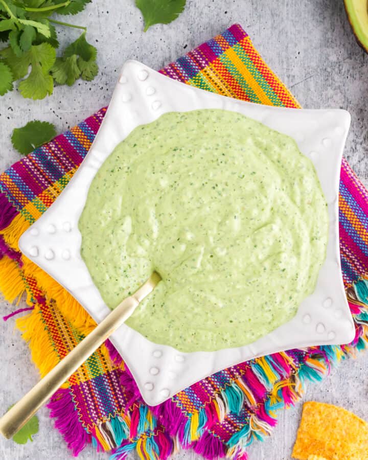 green avocado sauce for tacos in a white star-shaped bowl on a festive napkin.
