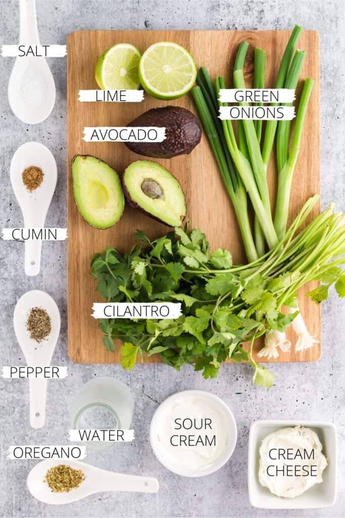 ingredients for creamy avocado sauce on a wooden cutting board.