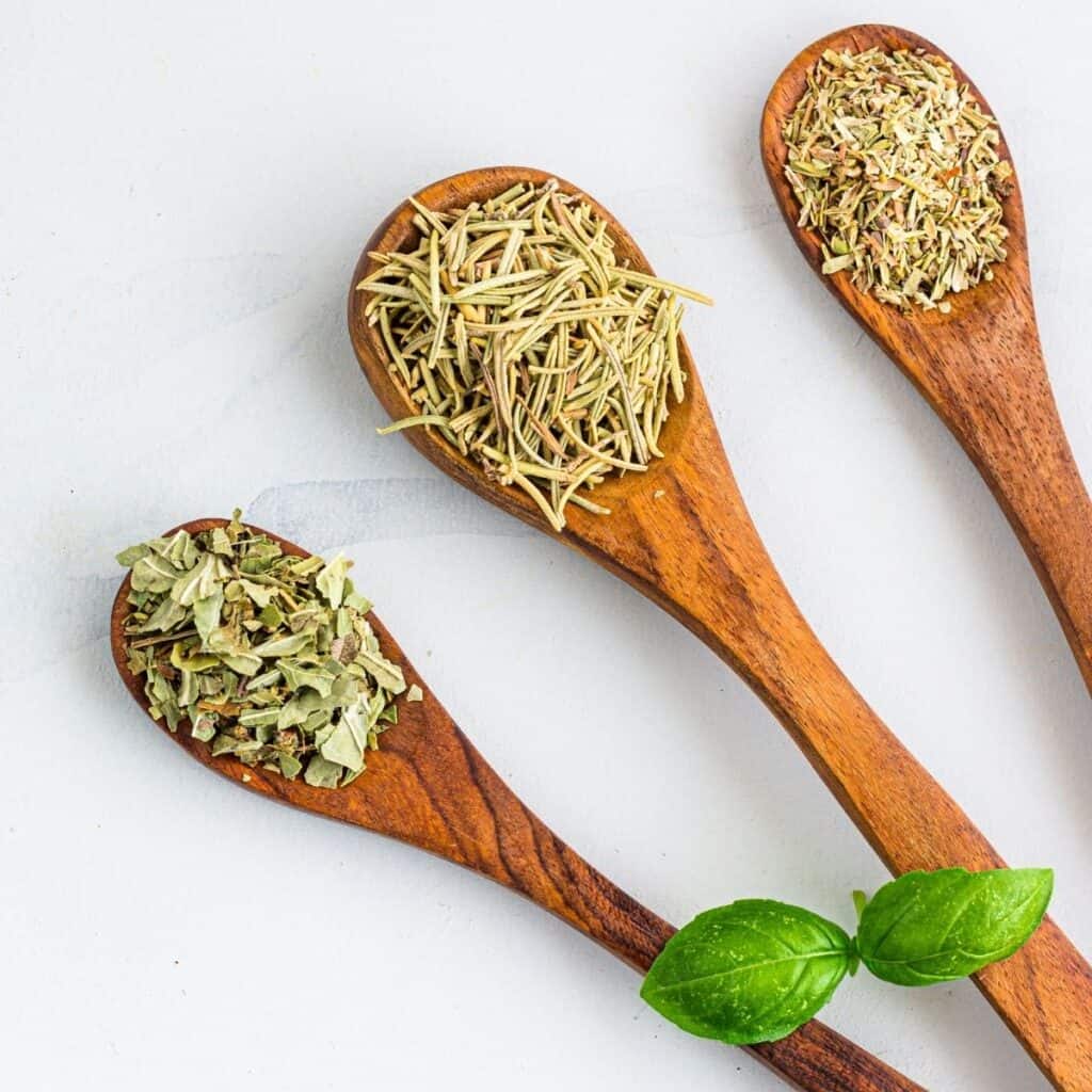 three wooden spoons filled with dried herbs.
