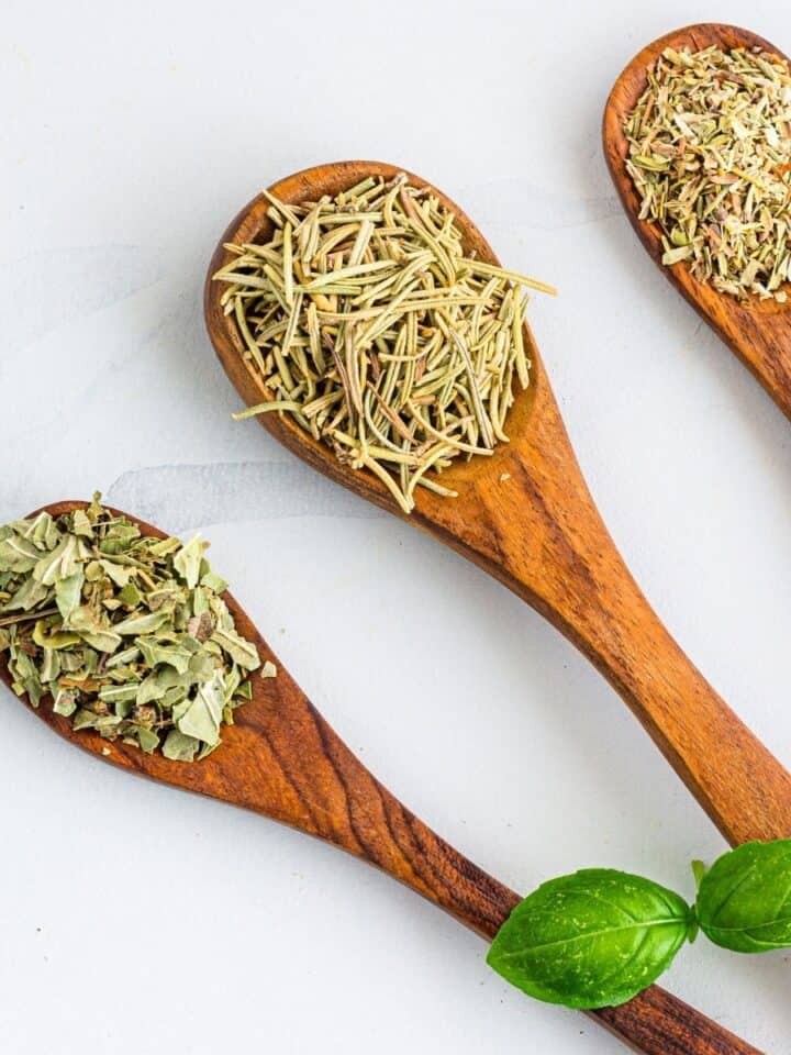 three wooden spoons filled with dried herbs.