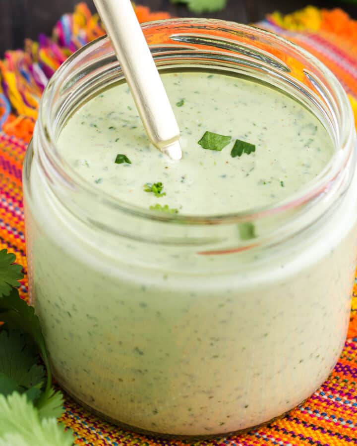 Glass jar filled with light green Cilantro Lime Sauce with Garlic sauce.
