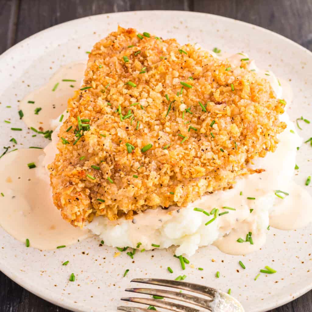 French Onion Pork Chops sitting on a bed of mashed potatoes covered in a creamy sauce.