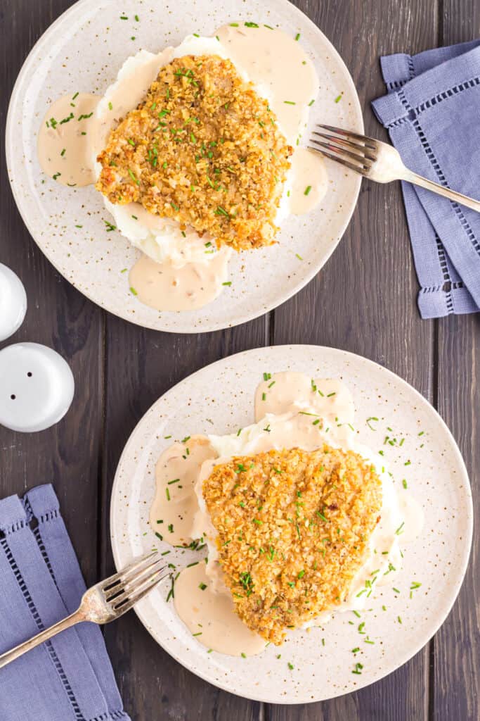 Two plates with French Onion Pork Chops served over mashed potatoes.