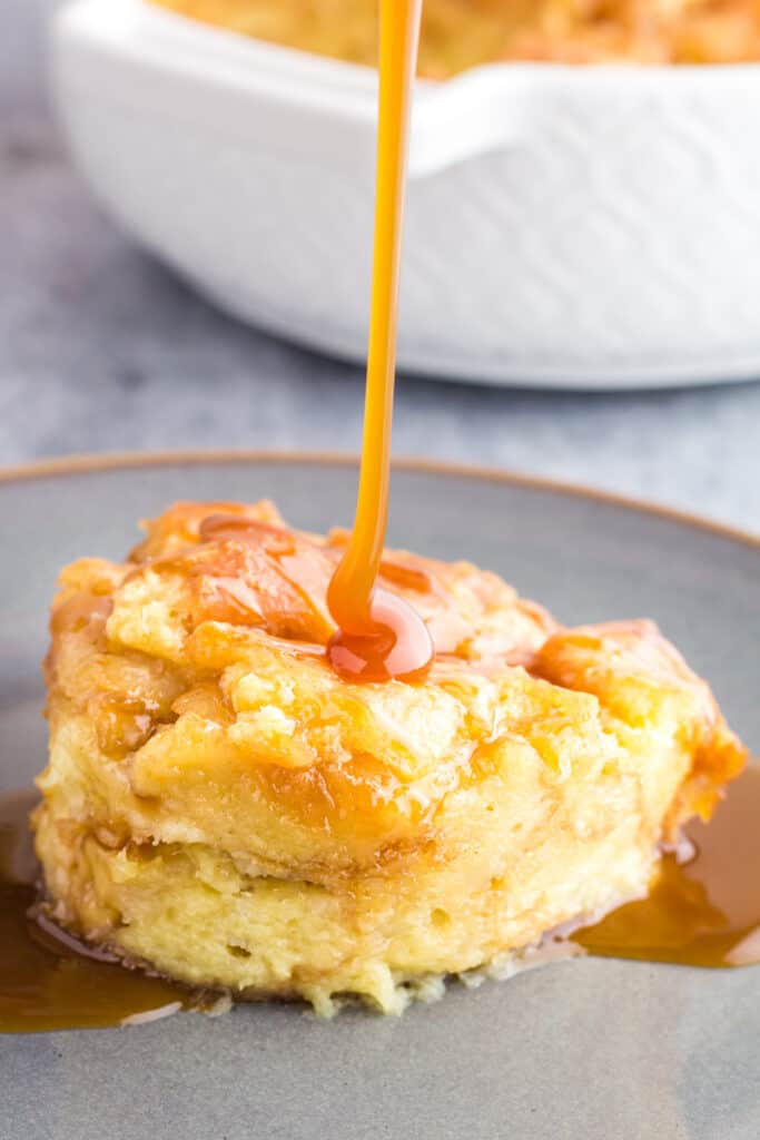 Scoop of donut bread pudding being drizzled with caramel sauce.