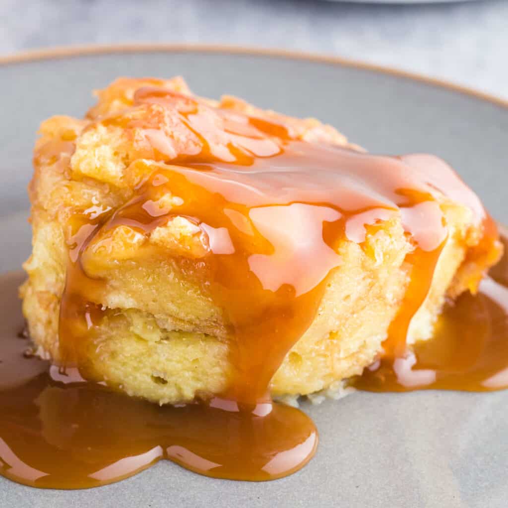 Scoop of donut bread pudding covered in caramel sauce.