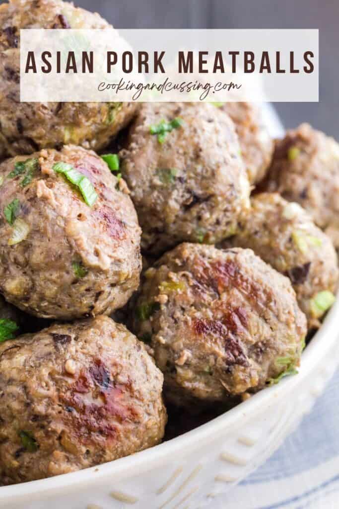 Close up of white bowl filled with brown meatballs sprinkled with green onions.