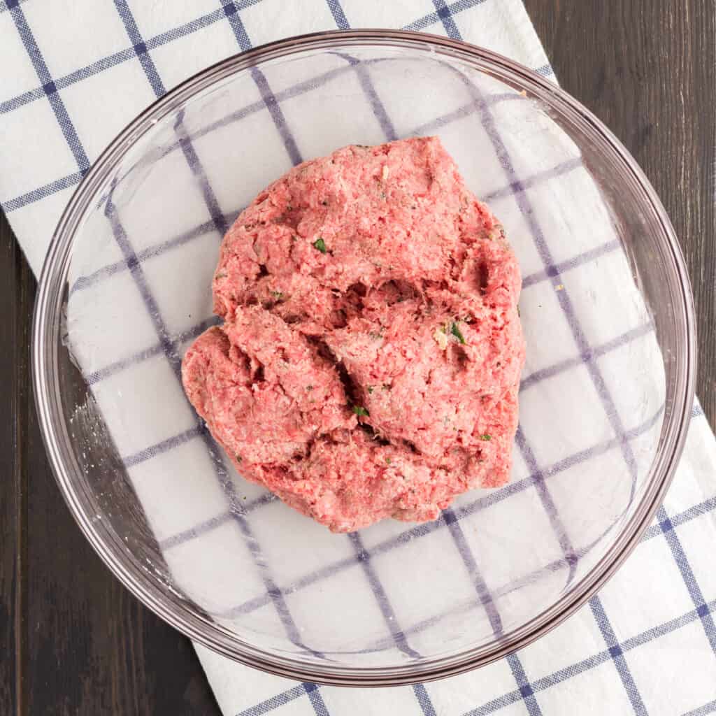 Mini meatball mix raw in a glass bowl.