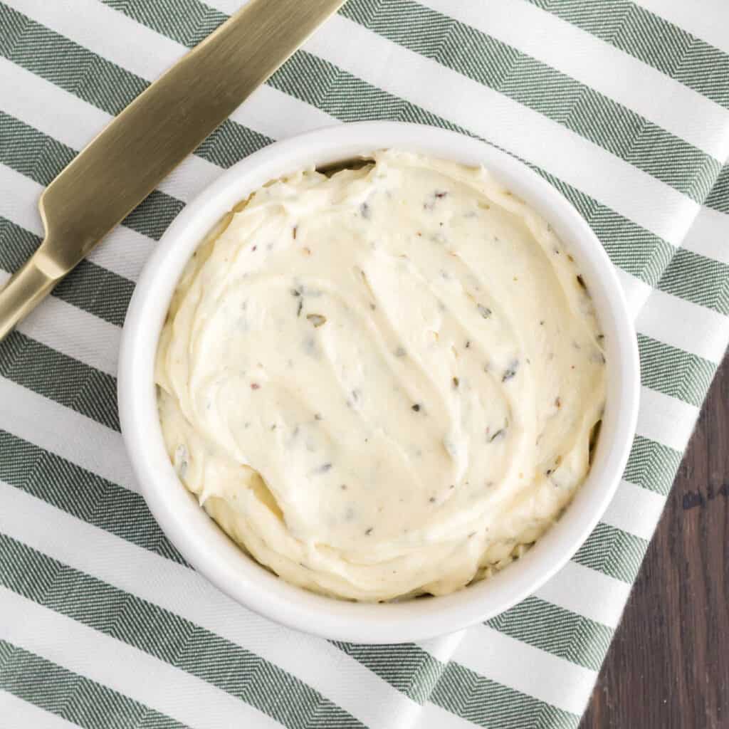 Boursin butter in a white ramekin on top of a green and white cloth.