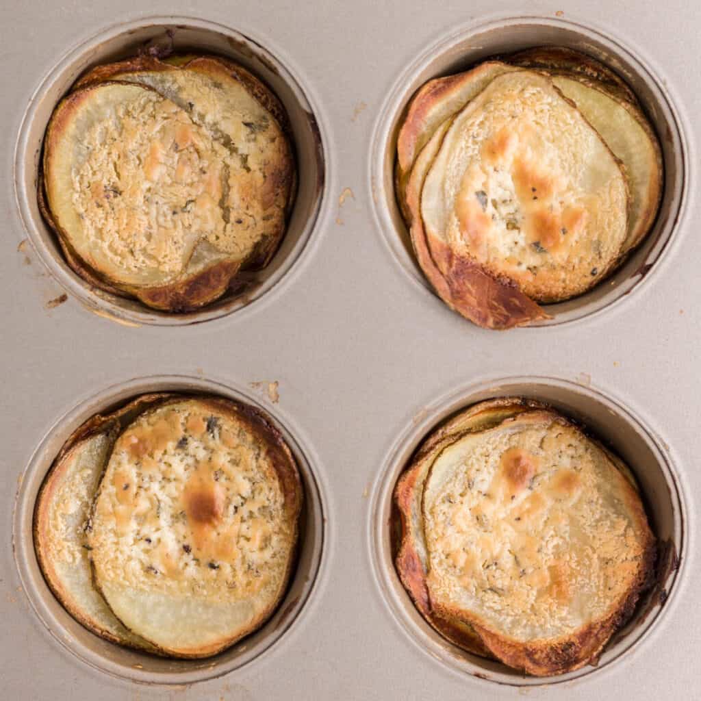 Four cooked potato stacks in the muffin pan.