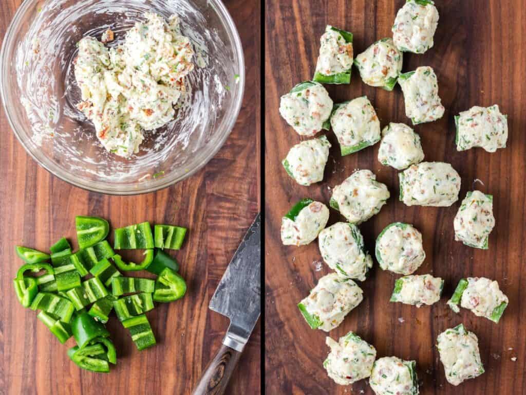 The jalapeno poppers being stuffed on a dark wooden cutting board.