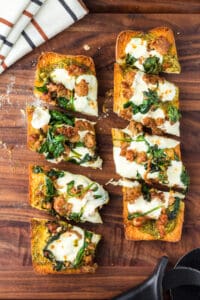 Air fryer french bread pizza sliced into pieces on a dark wooden cutting board