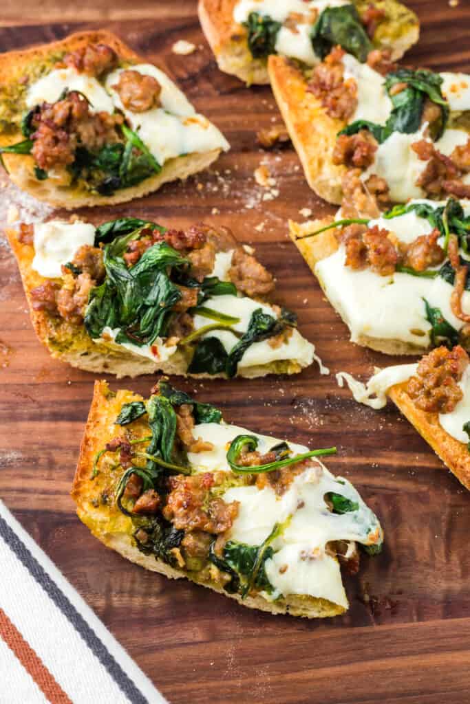 Air fryer french bread pizza sliced into pieces on a dark wooden cutting board