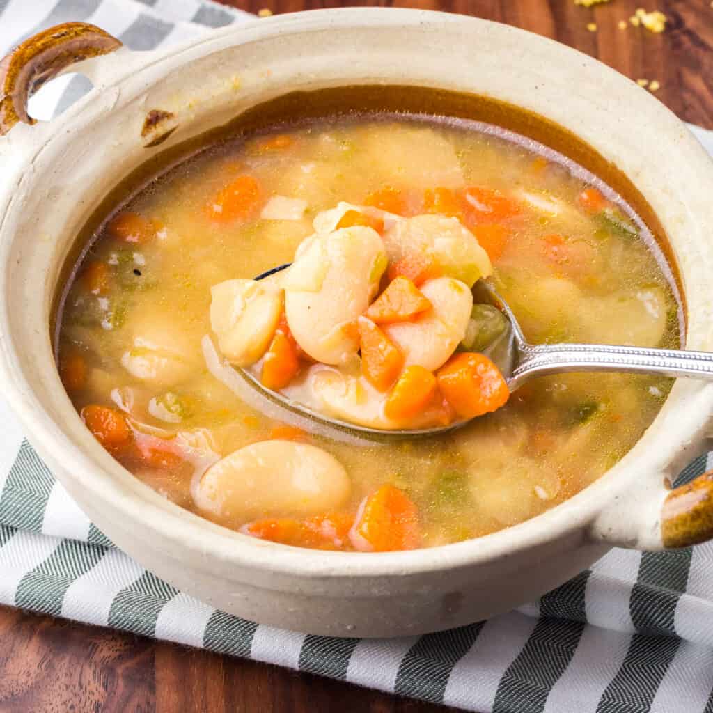 Bowlful of butter beans with a spoonful being lifted out.